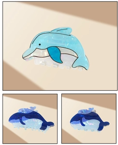 Detailed macro view of pearlescent blue whale and dolphin hair clips made of acetate