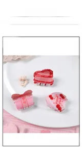 Tre mollette per capelli in acrilico rosa con ciliegie e torte su un piatto bianco