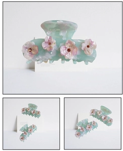 Détail de la pince à cheveux en résine menthe avec fleurs de cerisier et strass ambrés