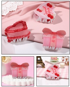Dettaglio macro di fermagli per capelli in acrilico rosa con ciliegia e confezione regalo