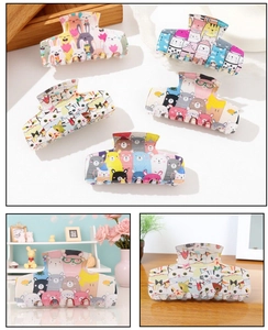 Set of five colorful cartoon animal hair claws in pink, blue and beige on wooden desk