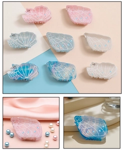 Detail of seashell and conch hair claws with pearlescent finish and blue rhinestones