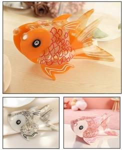 Detail view of goldfish acetate hair claws in orange, pink, and grey with scale patterns