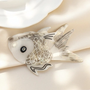 Elegant white acetate fish hair claw clip with pearlescent finish on champagne silk