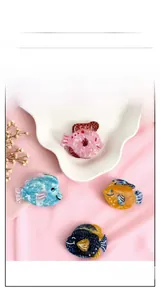 Vue détaillée de quatre pinces à cheveux poisson en acétate coloré avec texture marbrée et strass