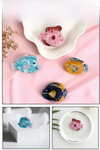 Détail de pinces à cheveux en acétate en forme de poisson aux couleurs pastel marbrées