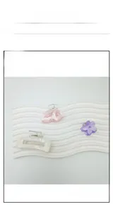 Detail of assorted pastel floral and geometric resin hair clips on a textured pedestal