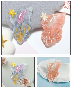 Detailed close-up of shell-shaped acetate hair claws with marble texture and starfish accents