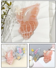 Detailed close-up of shell and starfish hair claws in pink marble and blue finishes