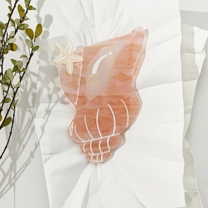 Shell-shaped acetate hair claw clip with starfish detail in pink orange translucent finish