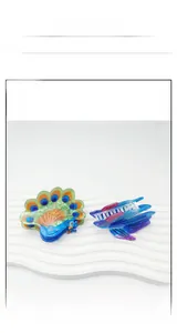 Detail view of colorful acetate hair claws in peacock and flying fish shapes on a stand