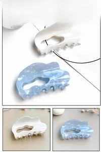 Detail of wavy French style hair claw clips in creamy white and marble blue textures