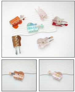 Close-up of violin and guitar shaped acrylic hair claws with marble texture finish