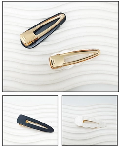 Detail view of acrylic hair clips in black and pearl white with golden alloy base