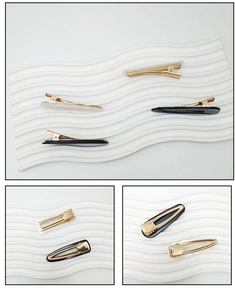 Close-up detail of golden metal hair clips with black and pearl white acrylic finish