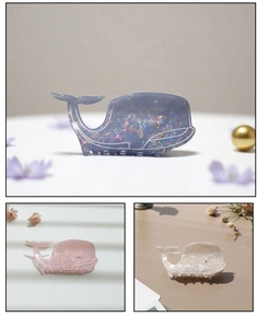 Detail of whale-shaped hair claws in iridescent blue, pink and white with rhinestones