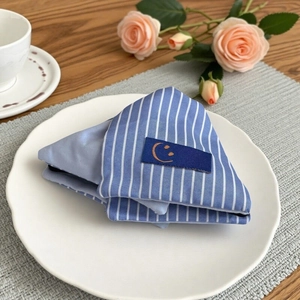 Blue and white striped triangle hair claw clip with a smile label on a white ceramic plate