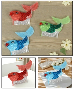 Detailed view of fish-shaped hair clips in blue, red, and green marble acetate finish