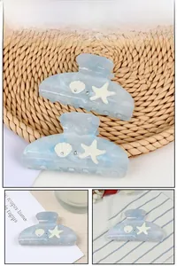 Detail view of ocean-inspired hair claws with blue marble texture, shells and starfish