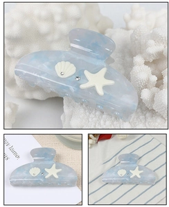 Close-up of ocean-style hair claw clip with shell and starfish on blue marble acetate
