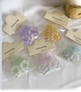 Detail of colorful floral hair clips with acrylic texture and plaid patterns on fabric