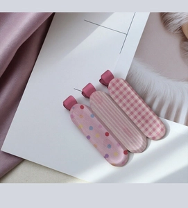 Detailed view of pink fabric duckbill hair clips with polka dots and stripes