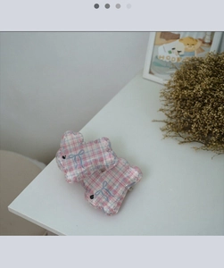 Detail of pink blue plaid bear hair clip with blue bow tie on white tabletop