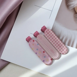 Three-piece pink plaid and polka dot bow hair clip set for girls displayed on white paper