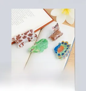 Detailed macro view of four animal-themed hair claws on an open book, matte finish