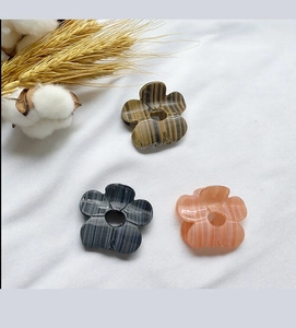 Tre mini mollette per capelli a fiori in marmo e legno su uno sfondo di tessuto rustico