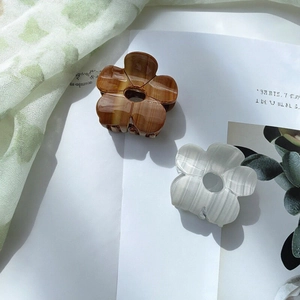 Mollette per capelli a fiori in acetato marrone e bianco perla su sfondo lifestyle