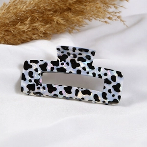 Elegant rectangle hollow hair claw clip with black and white cow pattern on white fabric