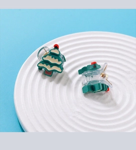 Detailed view of Christmas tree hair claws in green and beige on a white ceramic plate