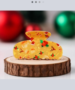 Détail d'une pince à cheveux de Noël jaune avec motifs de Père Noël et rennes