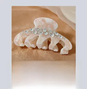 Close-up of pearl pink hair claw clip with sparkling rhinestones on satin fabric