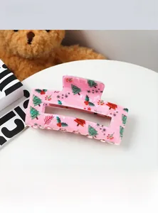 Détail d'une pince à cheveux rose avec motifs de sapins de Noël et de baies rouges