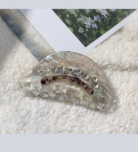 Detail of a pearlescent pumpkin hair claw clip with rhinestones on soft white fur