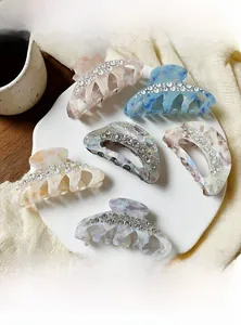 Detail showing acetate hair claws with marble texture and hand-set crystal rhinestones