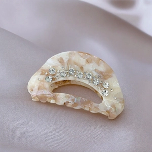 Elegant beige marble hair claw clip with rhinestones on a silk background