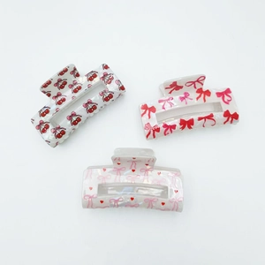 Three rectangular hair claws with sweet cherry and bow patterns in pearlescent finish