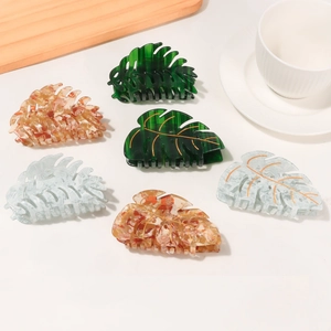 Leaf-shaped hair claws set with gold veins in green, amber, and blue acetate patterns