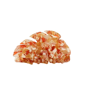 Artistic monstera leaf hair claw clip with orange marble resin texture on white backdrop