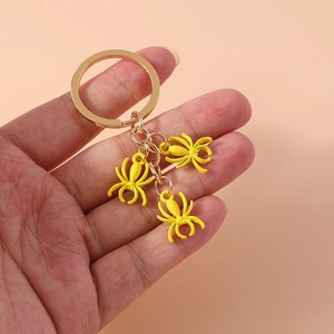 Close-up of golden keychain with three vibrant yellow spider charms for backpack