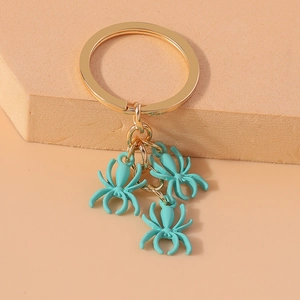 Detail of three mint green spider pendants on a gold-tone polished metal keyring