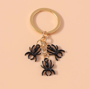 Detailed view of three black spider charms on a golden metal keychain ring