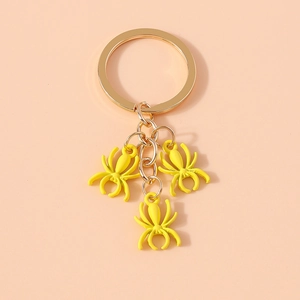 Detailed macro shot of three bright yellow spider charms on a golden metal keychain link