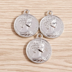 Gros plan de breloques en argent style pièce romaine avec relief d'Élisabeth II
