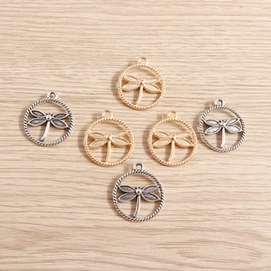 Detailed view of DIY dragonfly pendants in gold and antique silver finish on wood