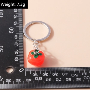 Macro detail of simulated red persimmon keychain pendant with weight label and ruler