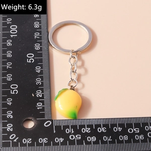 Detail view of mango keychain with size scale and weight 6.3g on beige background
